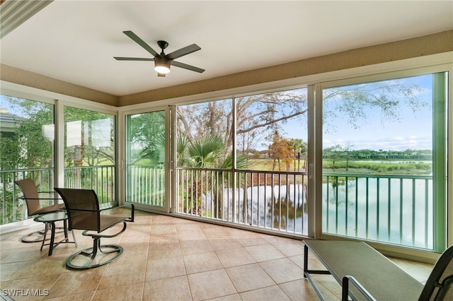 sunroom / solarium featuring ceiling fan, a healthy amount of sunlight, and a water view