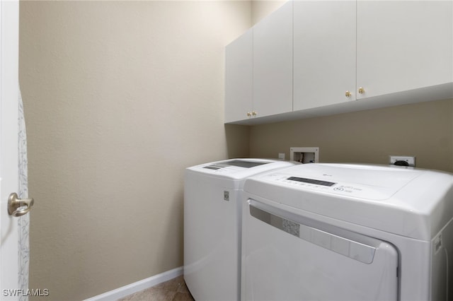 clothes washing area with light tile patterned flooring, cabinets, and washing machine and clothes dryer