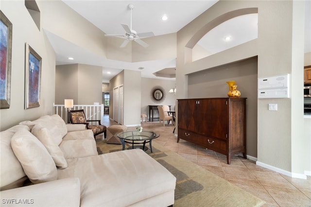 tiled living room with ceiling fan and a high ceiling