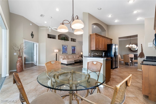 dining room with light tile patterned floors, ceiling fan with notable chandelier, and high vaulted ceiling