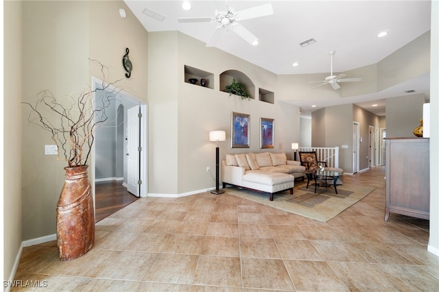 living room with ceiling fan and a towering ceiling