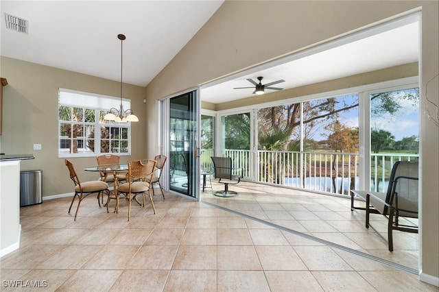 dining area featuring ceiling fan with notable chandelier, vaulted ceiling, and light tile patterned flooring