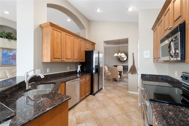 kitchen featuring an inviting chandelier, sink, vaulted ceiling, dark stone countertops, and stainless steel appliances