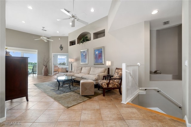 tiled living room with ceiling fan and a high ceiling