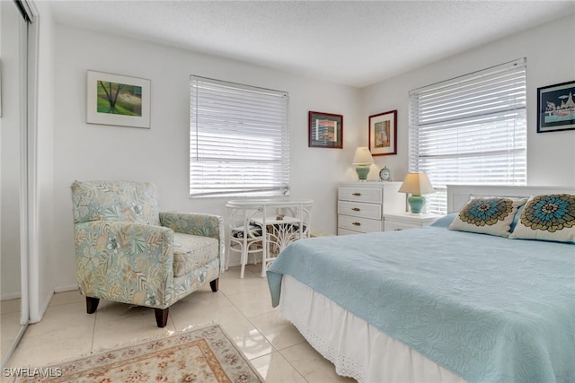 bedroom with a textured ceiling and light tile patterned floors