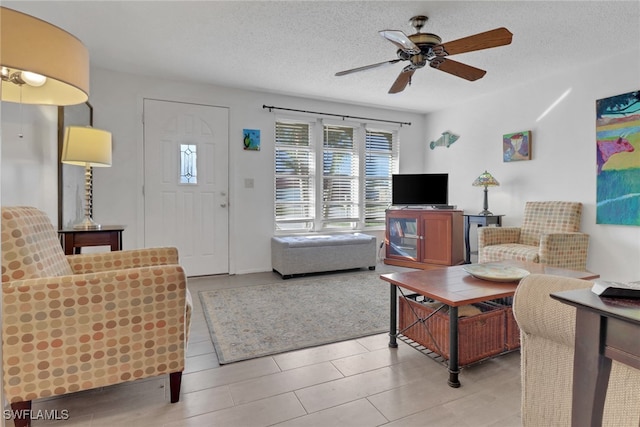 living room featuring ceiling fan, light tile patterned floors, and a textured ceiling