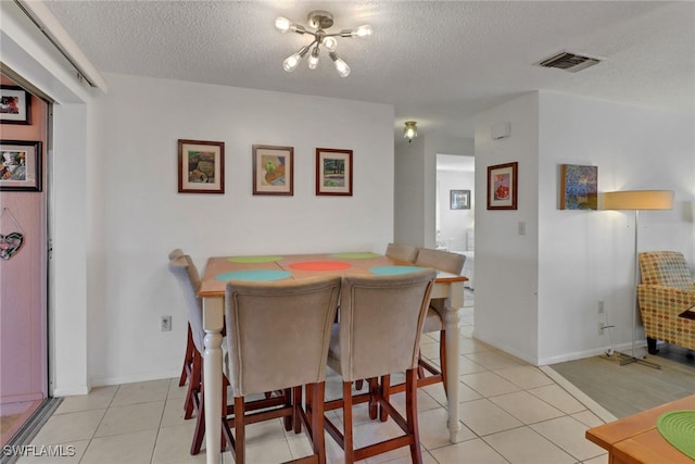 dining room featuring visible vents, a textured ceiling, and light tile patterned floors