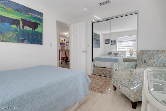 bedroom with light tile patterned floors, visible vents, and a closet