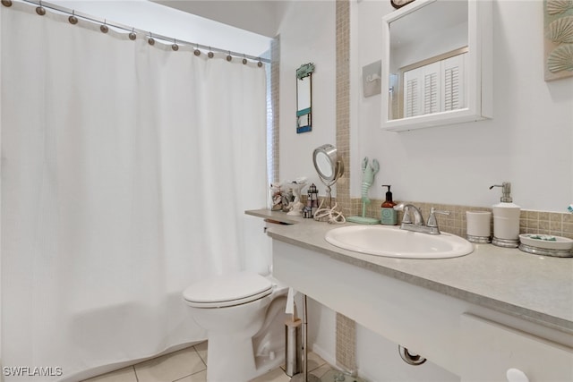 bathroom featuring shower / tub combo with curtain, a sink, toilet, and tile patterned floors