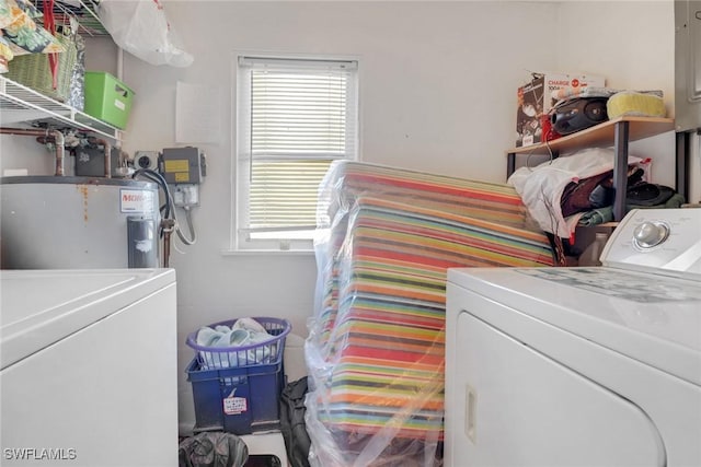 washroom featuring laundry area, water heater, and separate washer and dryer