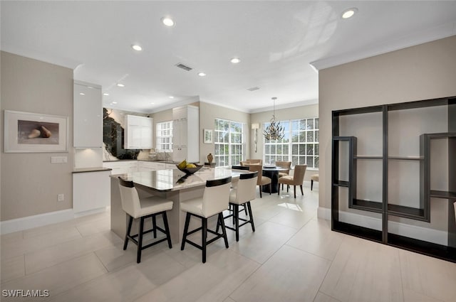 dining space with sink, light tile patterned floors, a notable chandelier, and ornamental molding