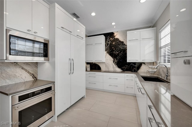 kitchen with backsplash, sink, white cabinetry, and stainless steel appliances