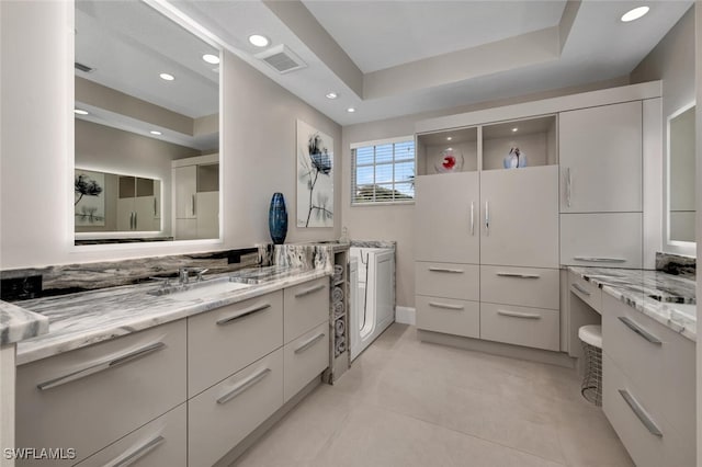 bathroom with tile patterned flooring, vanity, and a tray ceiling