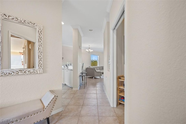 hall featuring crown molding, light tile patterned flooring, and an inviting chandelier