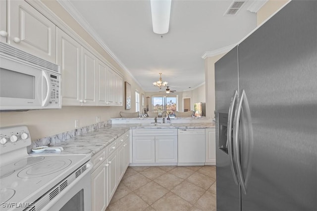 kitchen with white appliances, white cabinets, sink, crown molding, and light stone countertops