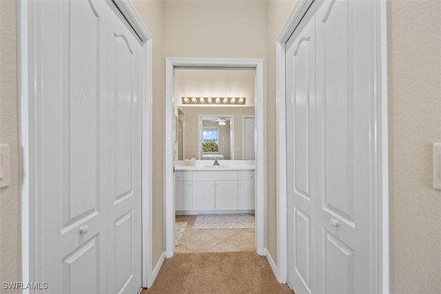 hall featuring sink and light carpet