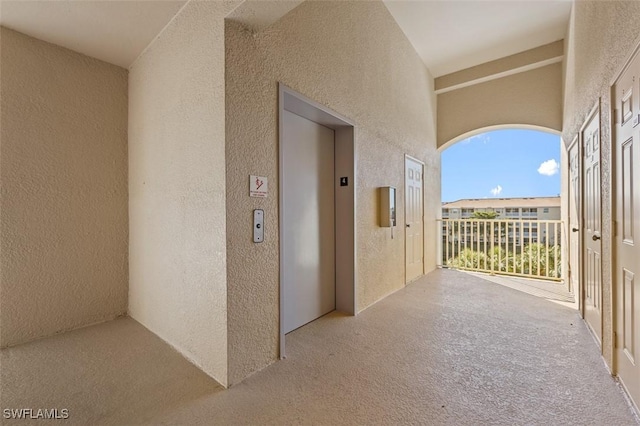 hall with light carpet and elevator