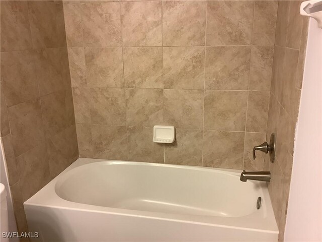 bathroom featuring tiled shower / bath combo and toilet