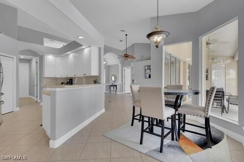 dining area featuring vaulted ceiling, ceiling fan, and light tile patterned flooring