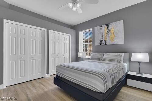 bedroom featuring light hardwood / wood-style flooring, ceiling fan, and multiple closets