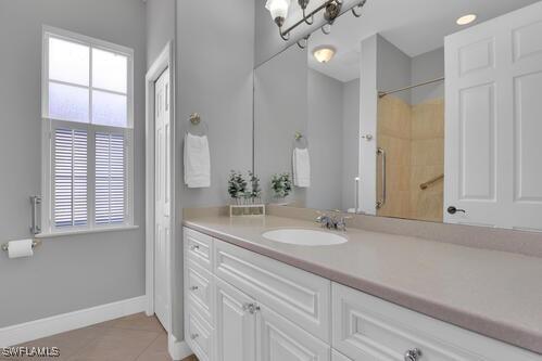 bathroom with tile patterned flooring, vanity, and walk in shower