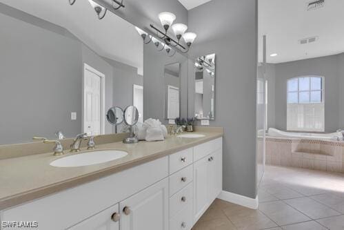 bathroom featuring tiled tub, tile patterned flooring, vanity, and an inviting chandelier