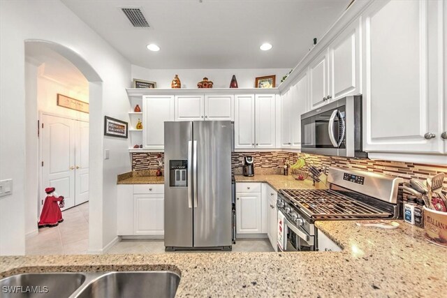 kitchen featuring stainless steel appliances, light stone countertops, visible vents, and white cabinetry