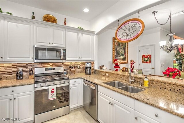 kitchen with appliances with stainless steel finishes, white cabinets, a sink, and tasteful backsplash