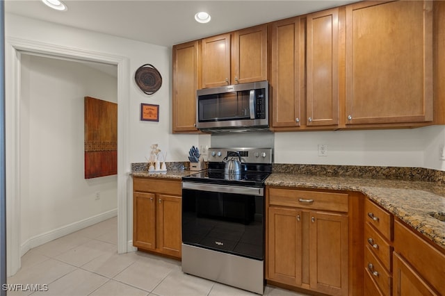 kitchen with light tile patterned flooring, stainless steel appliances, and stone countertops