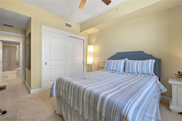 bedroom with ceiling fan, light carpet, and a closet