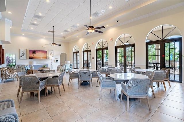 dining area with french doors, light tile patterned floors, a raised ceiling, and a high ceiling