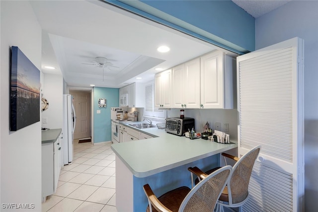 kitchen with white cabinetry, sink, ceiling fan, kitchen peninsula, and white appliances