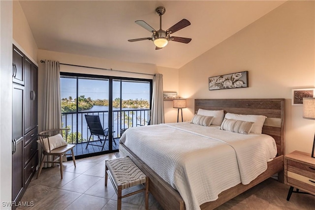 bedroom with ceiling fan, vaulted ceiling, access to outside, a water view, and dark tile patterned flooring