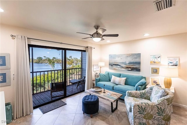 living room with a water view, ceiling fan, and light tile patterned floors