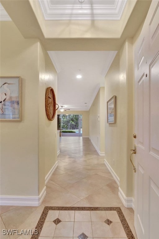 corridor with light tile patterned floors, baseboards, and ornamental molding