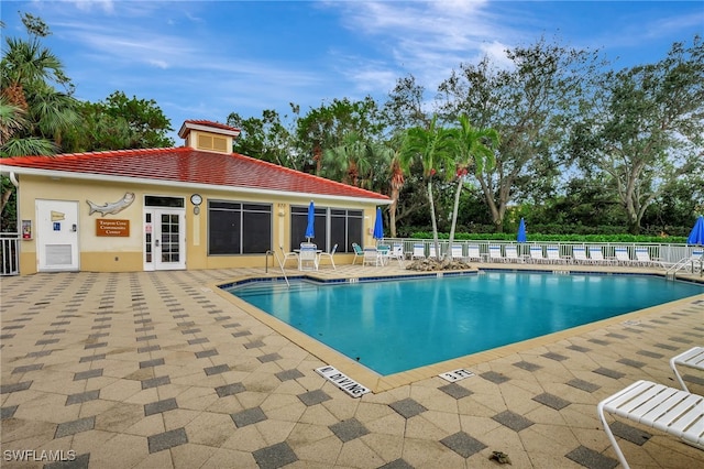 community pool with french doors, a patio, and fence