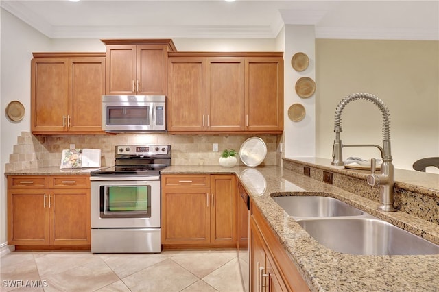 kitchen with backsplash, ornamental molding, brown cabinetry, stainless steel appliances, and a sink