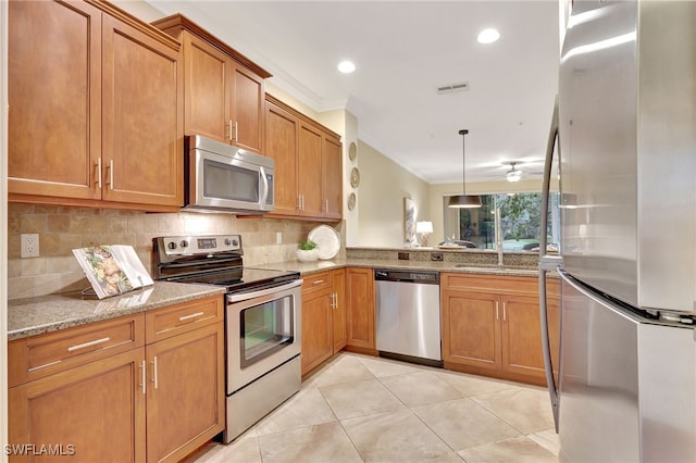 965 Tarpon Cove Dr Unit 103, Naples, FL 34110 - kitchen featuring stainless steel appliances, crown molding, light stone counters, brown cabinetry, and tasteful backsplash