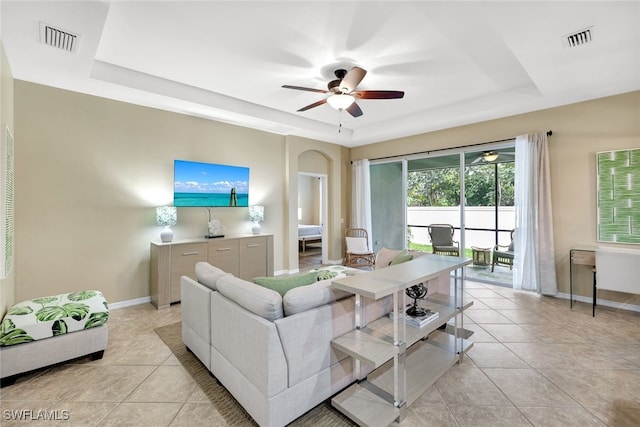 tiled living room featuring a raised ceiling and ceiling fan