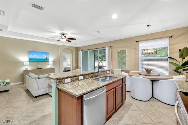 kitchen featuring light stone counters, ceiling fan with notable chandelier, stainless steel appliances, sink, and hanging light fixtures