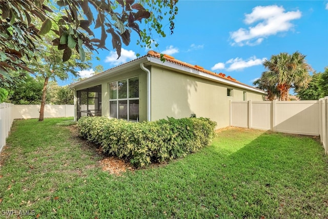 view of side of property with a sunroom and a lawn