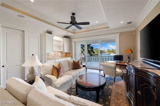 living area with ceiling fan, recessed lighting, visible vents, a tray ceiling, and crown molding