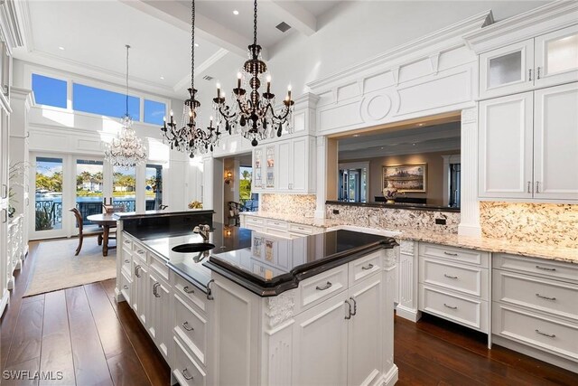 kitchen featuring beam ceiling, white cabinetry, dark hardwood / wood-style flooring, and hanging light fixtures