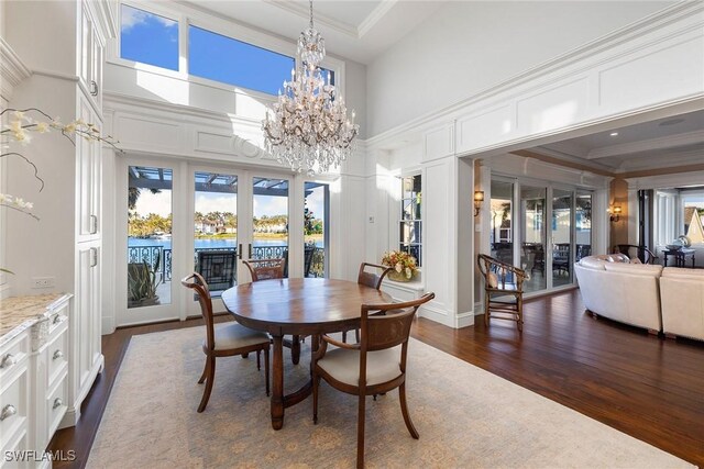 dining room featuring a high ceiling, an inviting chandelier, french doors, crown molding, and dark hardwood / wood-style floors