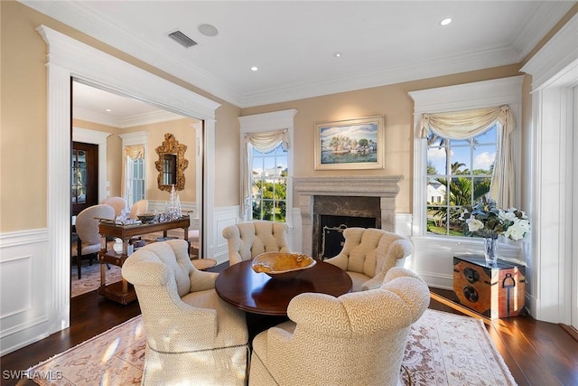 sitting room featuring a wainscoted wall, a premium fireplace, ornamental molding, and dark wood finished floors