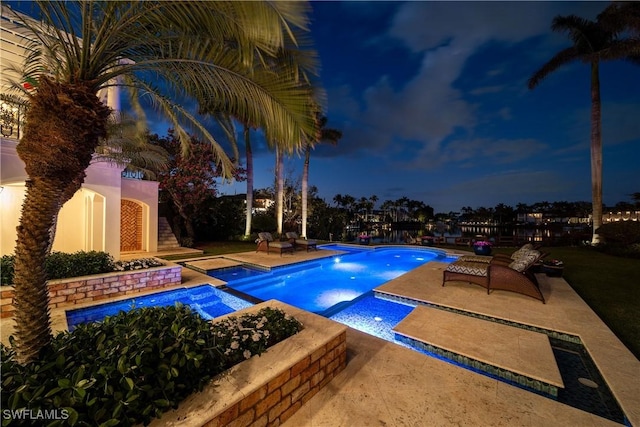 pool at twilight with a patio and a pool with connected hot tub