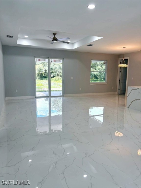 empty room featuring ceiling fan and a tray ceiling