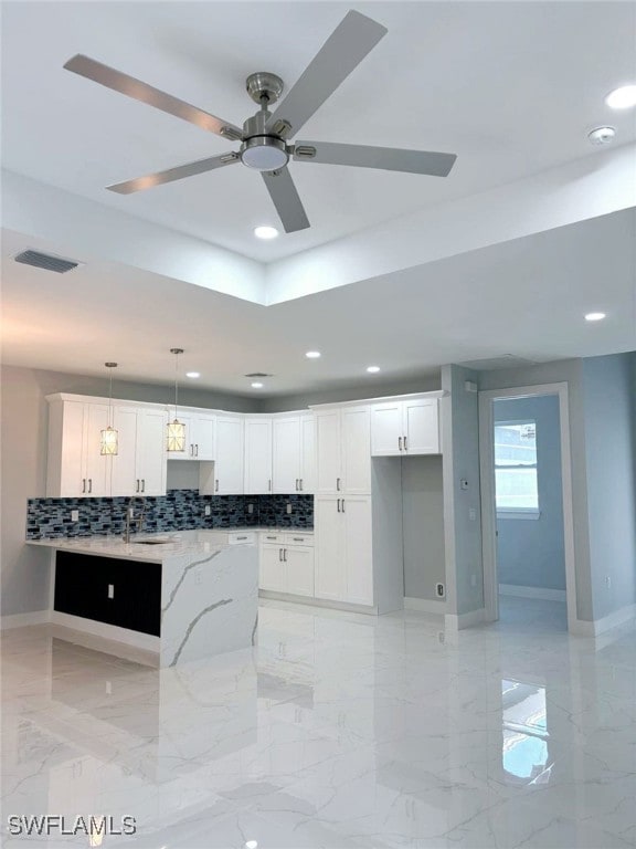 kitchen with white cabinetry, ceiling fan, light stone counters, backsplash, and pendant lighting