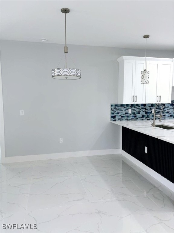 kitchen featuring white cabinetry, decorative backsplash, sink, and pendant lighting