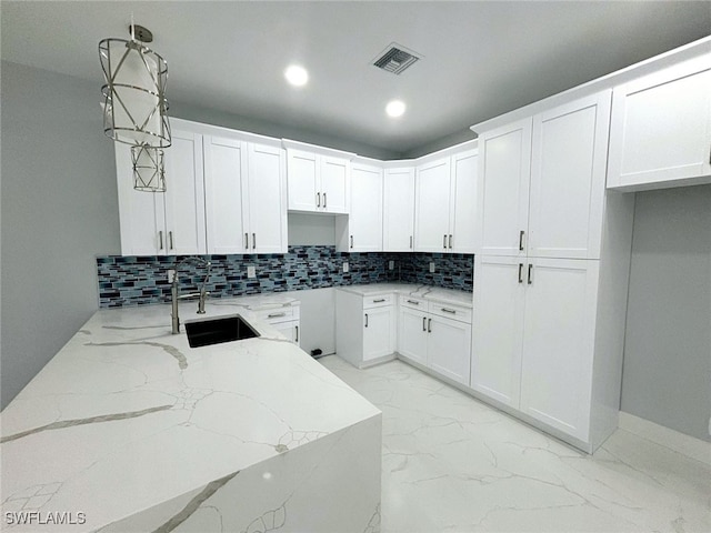 kitchen featuring white cabinets, decorative light fixtures, light stone counters, and backsplash